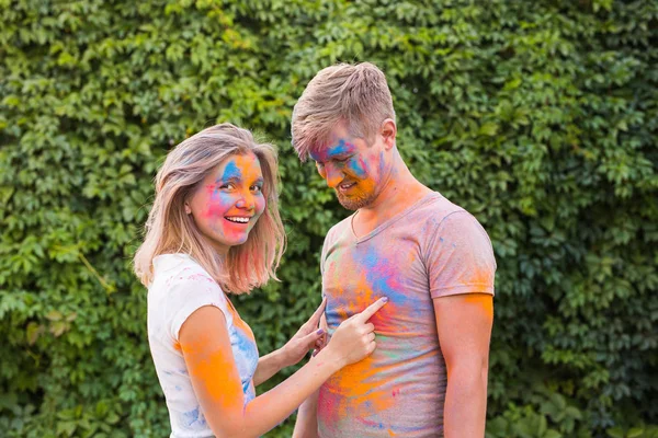 Amistad, festival de holi - mujer joven jugar con sucia camiseta de hombre joven en el festival de holi — Foto de Stock