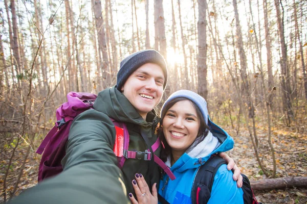 Äventyr, resor, turism, vandring och människor koncept - turister leende par tar selfie över träd bakgrund — Stockfoto
