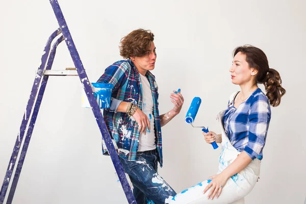 Reparação, renovação e amor conceito casal - jovem família fazendo redecoração e pintura paredes juntos e rindo . — Fotografia de Stock