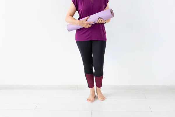 Joga, koncepcja ludzie - zbliżenie kobieta trzyma mat po zajęciach jogi na białym tle z miejsca kopii — Zdjęcie stockowe