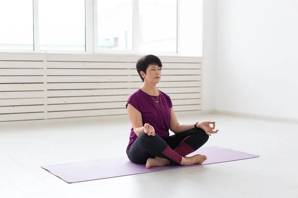 Yoga, harmony, people concept - Middle aged woman sitting in lotus position