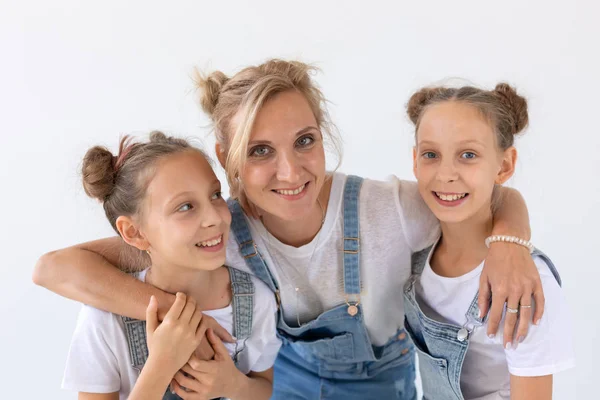 Concepto de personas, familia e hijos - retrato de una madre encantadora abrazando a sus hijas gemelas sobre fondo blanco — Foto de Stock