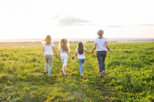 Family, summer and holiday concept - Group of women and girls going away in green field — Stock Photo, Image