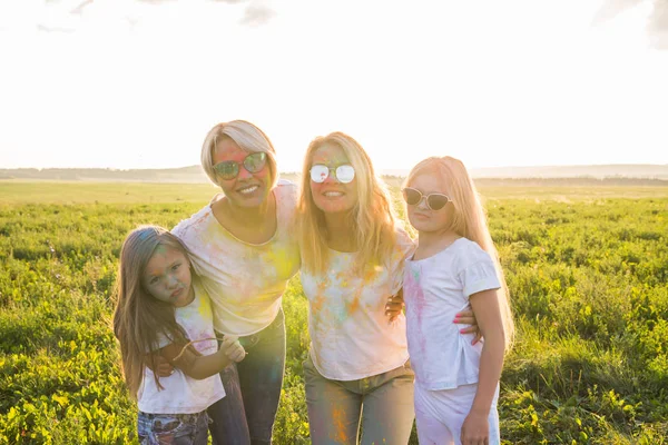 Festival de holi, la amistad, la felicidad y el concepto de vacaciones - Chicas felices y divertidas cubiertas de pintura en el campo verde —  Fotos de Stock