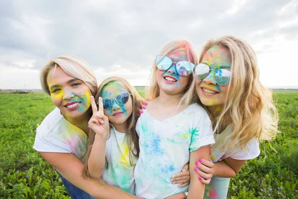 Amistad, vacaciones, concepto de color - amigos sonriendo y divirtiéndose en colores en el festival de holi —  Fotos de Stock