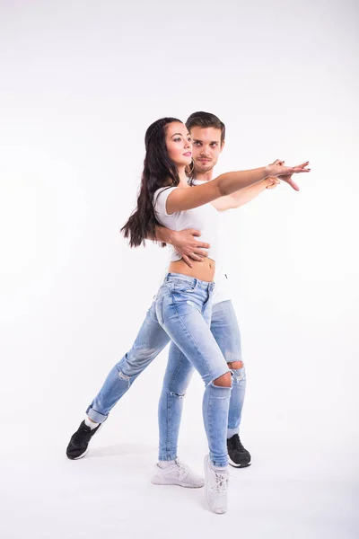 Молода пара танцює соціальні танці холота, меренг, сальса, кімоба. Дві елегантні пози на білій кімнаті . — стокове фото