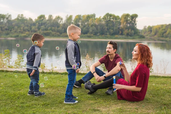 Familjen och naturen koncept - mamma, pappa och deras barn som leker med färgglada såpbubblor — Stockfoto