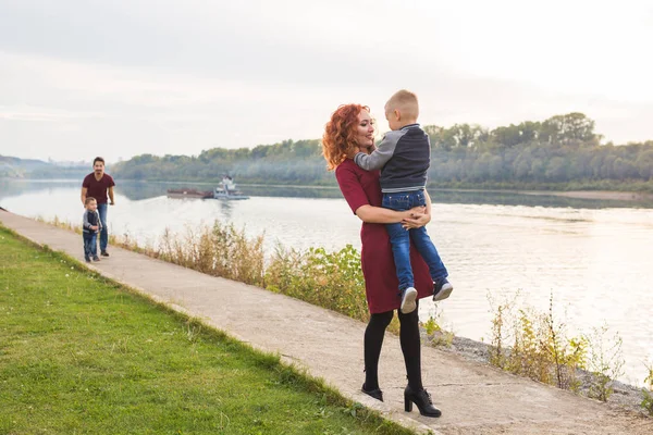 Family and children concept - Redhead woman holding her son over water background — Stock Photo, Image