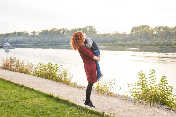 Mutterschafts- und Kinderkonzept - junge Mutter mit Sohn im Arm in der Nähe des Flusses — Stockfoto