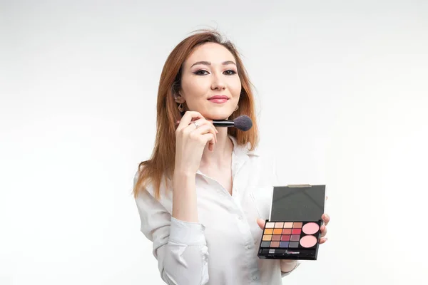 Visagistin, Schönheits- und Kosmetikkonzept - koreanische Visagistin mit Make-up-Pinseln und Lidschatten-Palette auf weißem Hintergrund — Stockfoto