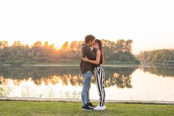 Kärlek, romantiska, naturen, människor koncept - unga vackra paret tittar på varandra och kramas nära sjön — Stockfoto