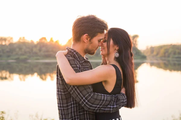 Relation, kärlek och natur koncept - närbild porträtt av attraktiv kvinna och stilig man kramas på bakgrunden av sjön — Stockfoto