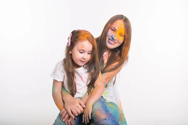 Família, festival de holi e conceito de pessoas mulher e pequena filha se divertindo com pó colorido no fundo branco — Fotografia de Stock