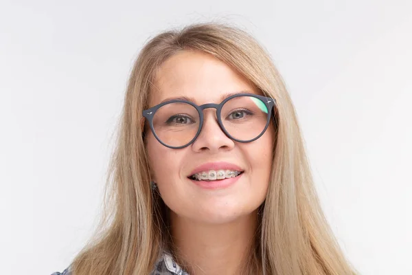 Здоровье зубов, стоматология и коррекция укусов - счастливая улыбающаяся женщина в очках с брекетами на белом фоне — стоковое фото