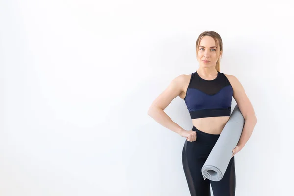 Concepto de personas, fitness y deporte - Mujer atractiva y saludable sosteniendo alfombra gris sobre fondo blanco con espacio para copiar —  Fotos de Stock