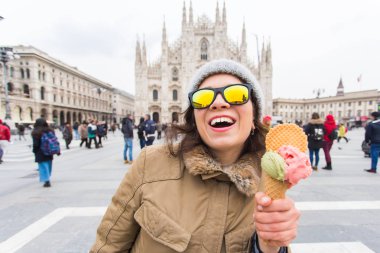 Genç ve mutlu kadın turist dondurma Milano'da ünlü Duomo Katedrali önünde ayakta. Milano mutlu tatiller