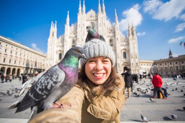 Kış seyahat, tatil ve kuşlar kavramı - genç mutlu kadın turist Milano'da ünlü Duomo Katedrali önünde selfie fotoğraf yapma komik güvercinler ile.