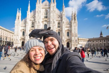 Seyahat ve tatil kavramı - Milano Duomo Katedrali önünde komik güvercinler ile kendi kendine portre alarak mutlu turistler kış