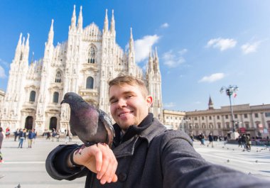 Kış seyahat, tatil ve kuşlar kavramı - yakışıklı erkek turist Milano'da ünlü Duomo Katedrali önünde selfie fotoğraf yapma komik güvercinler ile.