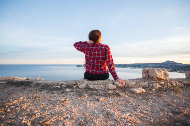 Seyahat, macera ve doğa kavramı - kadın turist dağda tek başına oturmak