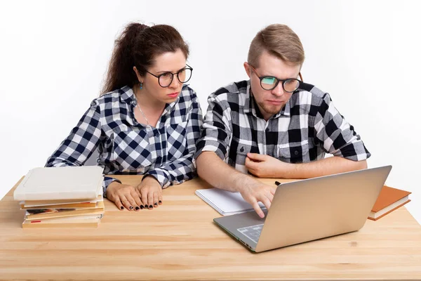 Menschen und Bildungskonzept - zwei verdutzte Studenten in karierten Hemden sitzen am Tisch — Stockfoto