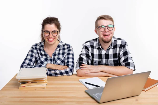 Educación, estudiantes, concepto de personas - pareja divertida de adolescentes con gafas parecen nerds sentados en la mesa — Foto de Stock