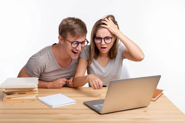 Menschen und Bildungskonzept - zwei fröhliche lustige Studenten sitzen am Holztisch mit Laptop und Büchern — Stockfoto