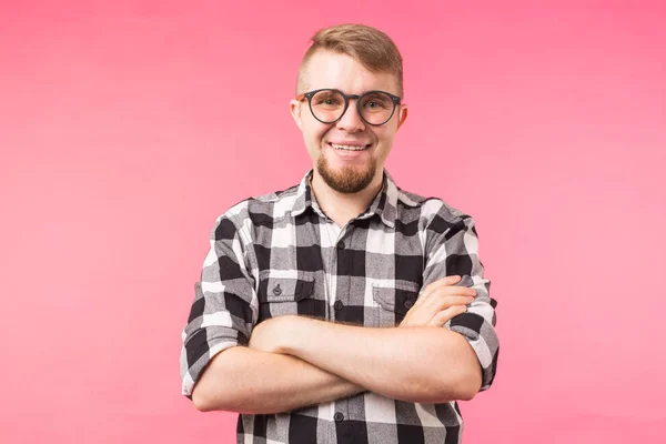 Retrato de hombre guapo de moda feliz en camisa a cuadros y gafas cruzando las manos sobre fondo rosa — Foto de Stock