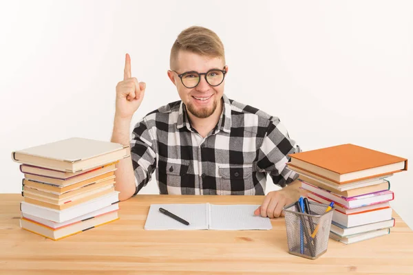 Concepto de personas, conocimiento y educación - Estudiante inteligente sentado a la mesa con libros y cuaderno — Foto de Stock