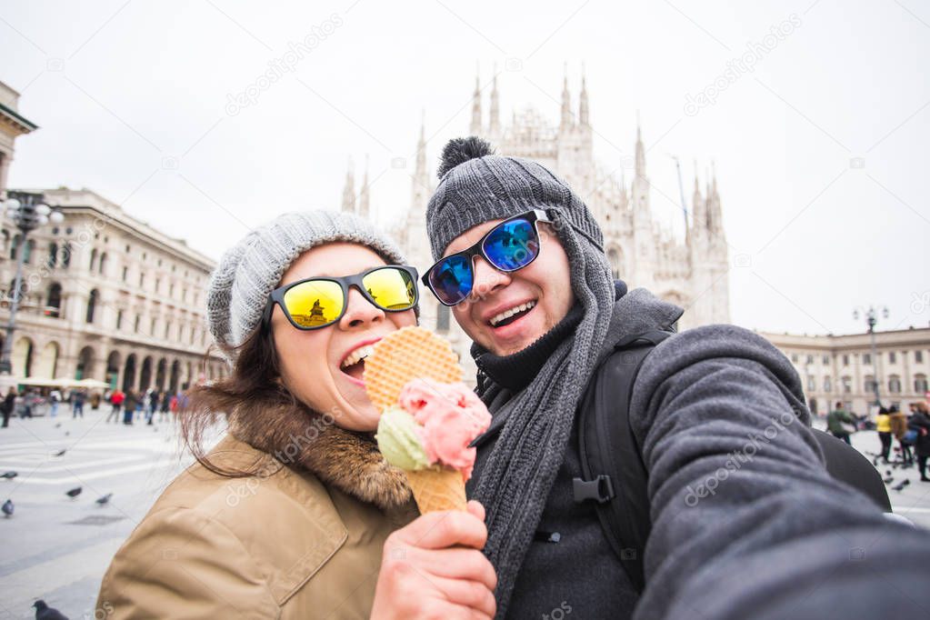 Travel in winter concept - Young and happy tourist making selfie photo in front of the famous Duomo cathedral in Milan. Happy vacations in Milan