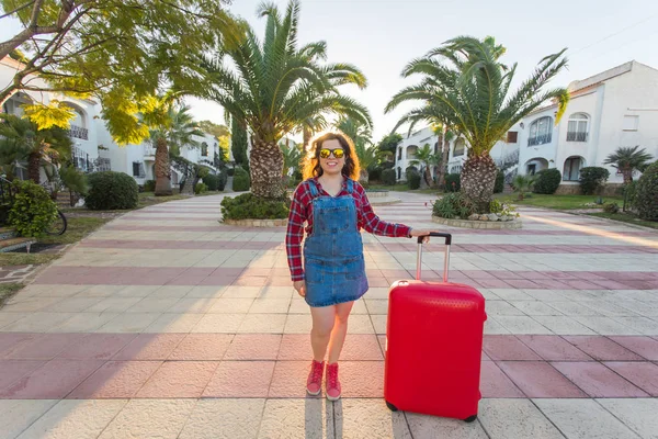 Viajes, turismo y gente concepto - mujer joven y feliz va a viajar con maleta roja y sonriendo — Foto de Stock