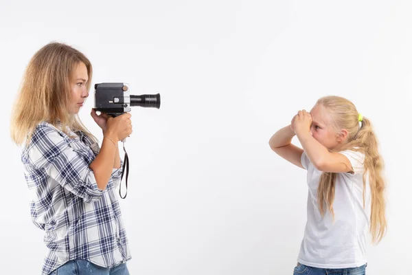 Technológiák, a fényképezés és a fő koncepció - szőke fiatal nő, retro fényképezőgép, fényképezés egy kislány felső fehér háttér — Stock Fotó