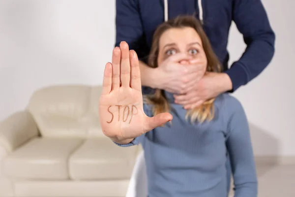 Persone, violenza domestica e concetto di abuso - La donna mostra smettere di abusare segno su sfondo mans. L'uomo le copre la bocca con la mano — Foto Stock