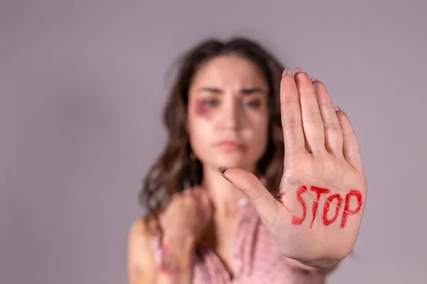 Domestic violence, protesting and people concept - brunette woman expressing denial with STOP on her hand on grey room — Stock Photo, Image