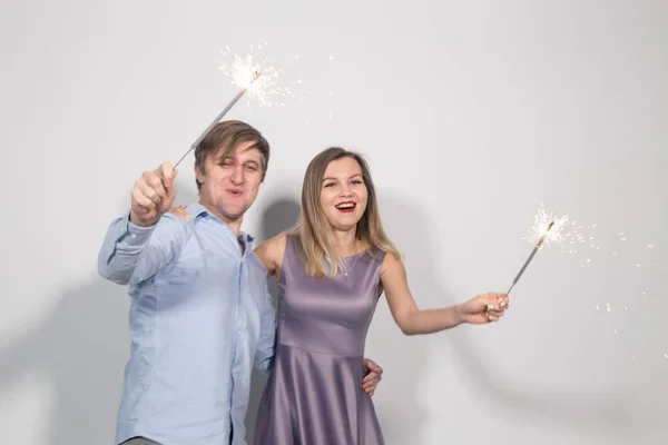 Festa, diversão e feriados conceito - jovem casal feliz com sparklers no fundo branco — Fotografia de Stock