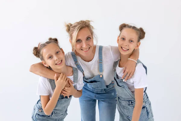 Concepto de personas, familia e hijos - retrato de una madre encantadora abrazando a sus hijas gemelas sobre fondo blanco — Foto de Stock
