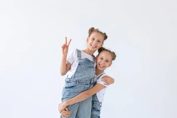 Concepto de familia y amor: dos hermanas gemelas sonrientes abrazándose sobre un fondo blanco — Foto de Stock