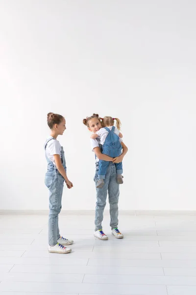 Concepto de personas, familia e hijos - hermanas gemelas con su hermana pequeña en las manos — Foto de Stock