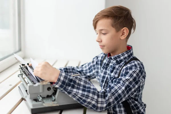 Gente, niños y concepto de estilo - niño con vieja máquina de escribir negro sobre fondo blanco — Foto de Stock