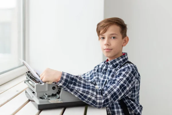 Día Mundial del concepto de escritor - Niño con una vieja máquina de escribir sobre el fondo de la ventana —  Fotos de Stock