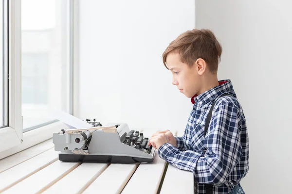 Gente, niños y concepto de estilo - niño con vieja máquina de escribir negro sobre fondo blanco . —  Fotos de Stock