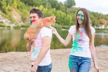 Festival holi, turizm ve doğa kavramı - kadın ve erkek kedi ile portre çok renkli toz kaplı.