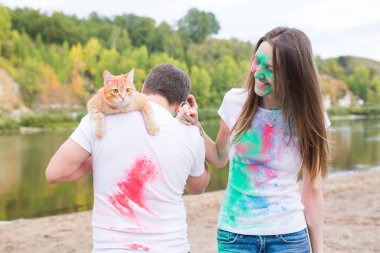 Evde beslenen hayvan, yaz turizm, festival holi ve doğa kavramı - komik erkek ve kadın ile kedi doğal zemin üzerine