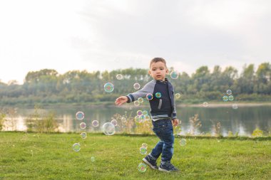 Çocukluk, mutluluk, insanlar kavramı - sabun köpüğü ile çalışan genç çocuk