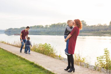 Aile ve çocuk kavramı - anne, baba ve iki oğlu yaz saati, nehir kenarında oynarken zevk