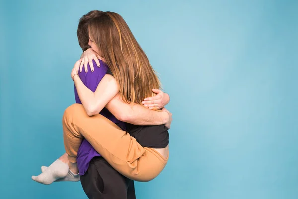 Gente, relación y concepto divertido - Hombre sonriente sosteniendo hermosa mujer sobre fondo azul — Foto de Stock