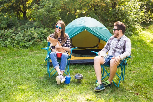 Gente, turismo de verano y concepto de naturaleza - pareja joven sentada cerca de una tienda de campaña —  Fotos de Stock