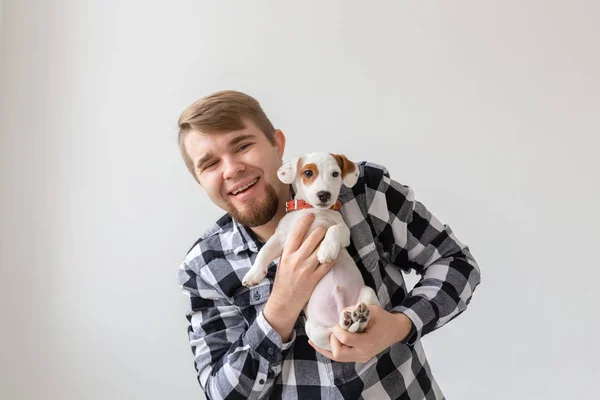 Conceito de pessoas, animais de estimação e animais - close-up de jovem segurando Jack Russell terrier filhote de cachorro no fundo branco — Fotografia de Stock