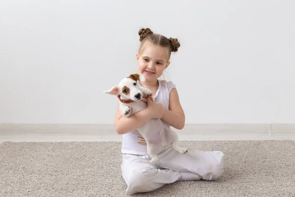 Mascotas, concepto de la infancia y los animales - Retrato de niña sentada en el suelo con el cachorro Jack Russell Terrier — Foto de Stock