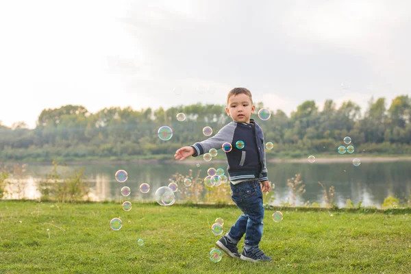 Infância, felicidade, conceito de pessoas - menino correndo pelas bolhas de sabão — Fotografia de Stock